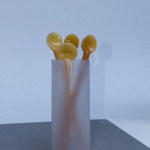 Lang mat glas met enkele gele honing lepels er in.