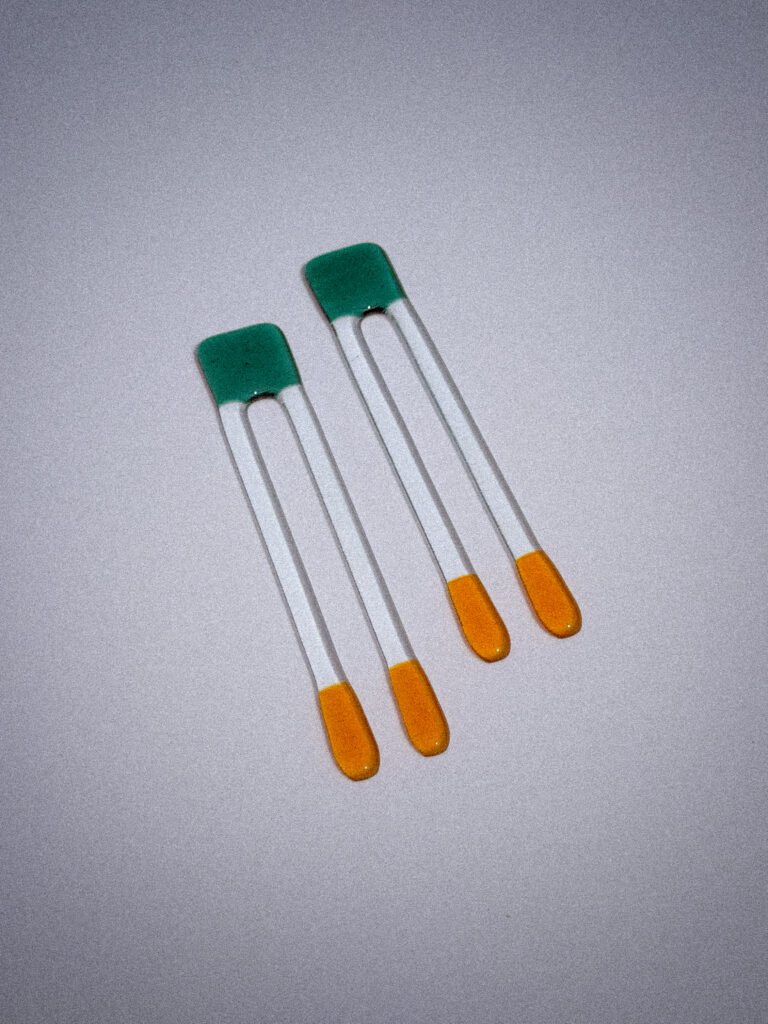 Handgemaakte glazen Pool Sticks in groen en goud op een witte tafel.