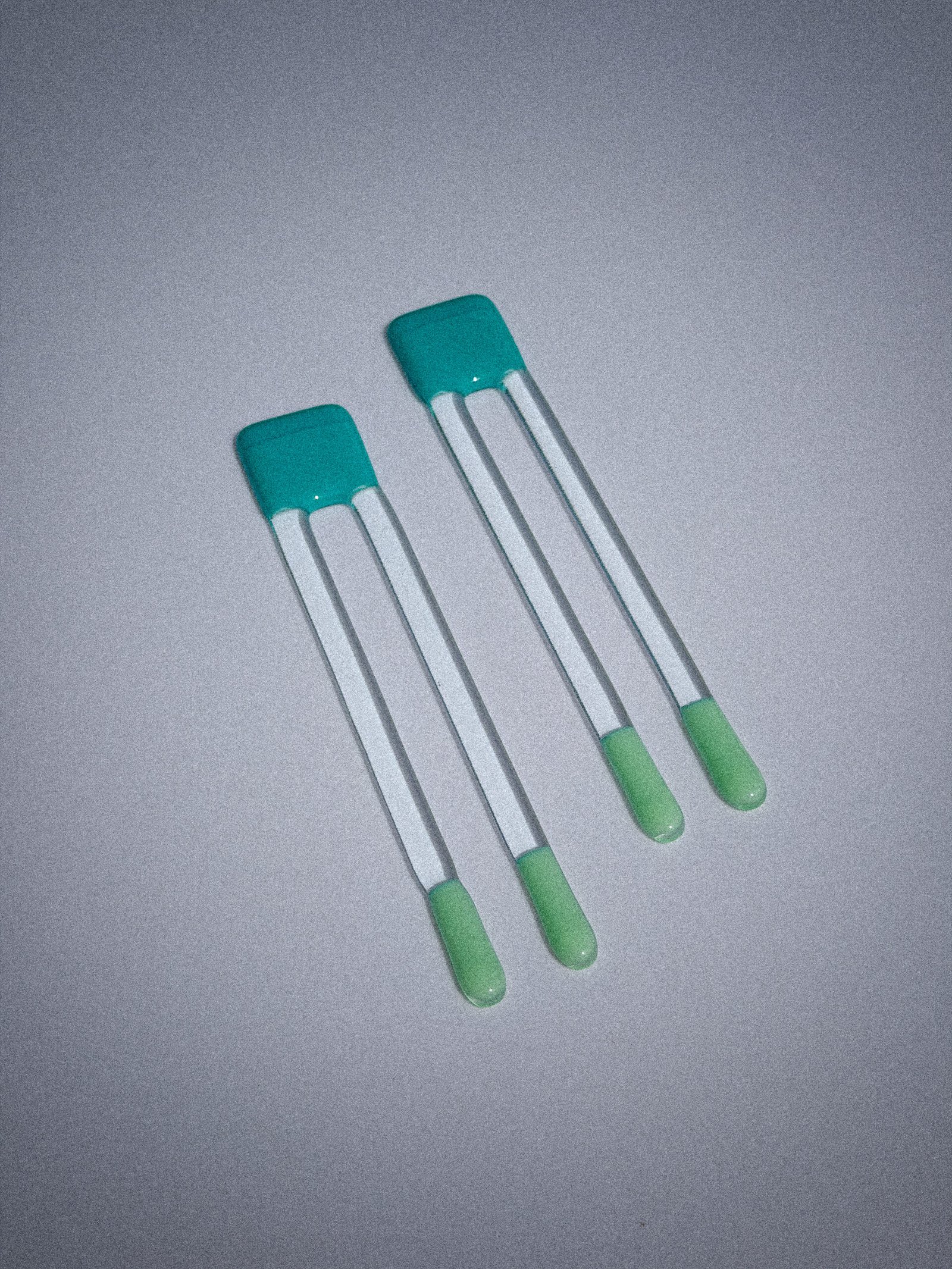 Handgemaakte glazen Pool Sticks in aqua en azuur op een witte tafel.