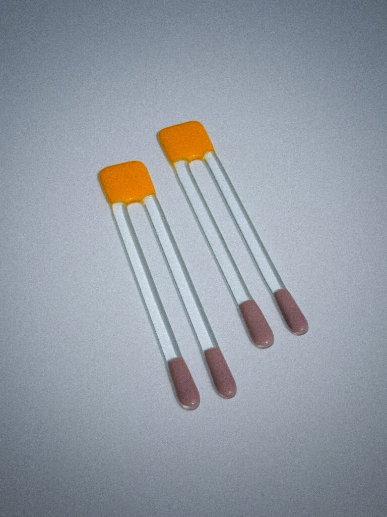 Handgemaakte glazen Pool Sticks in geel en paars op een witte tafel.