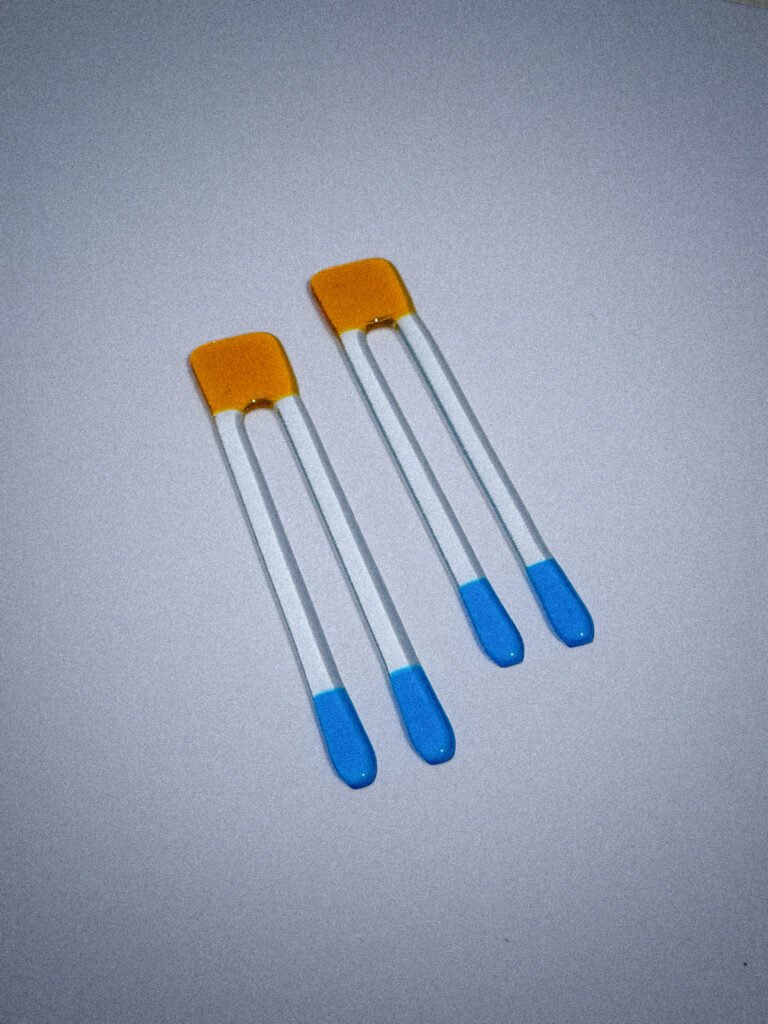 Handgemaakte glazen Pool Sticks in honinggeel en blauw op een witte tafel.