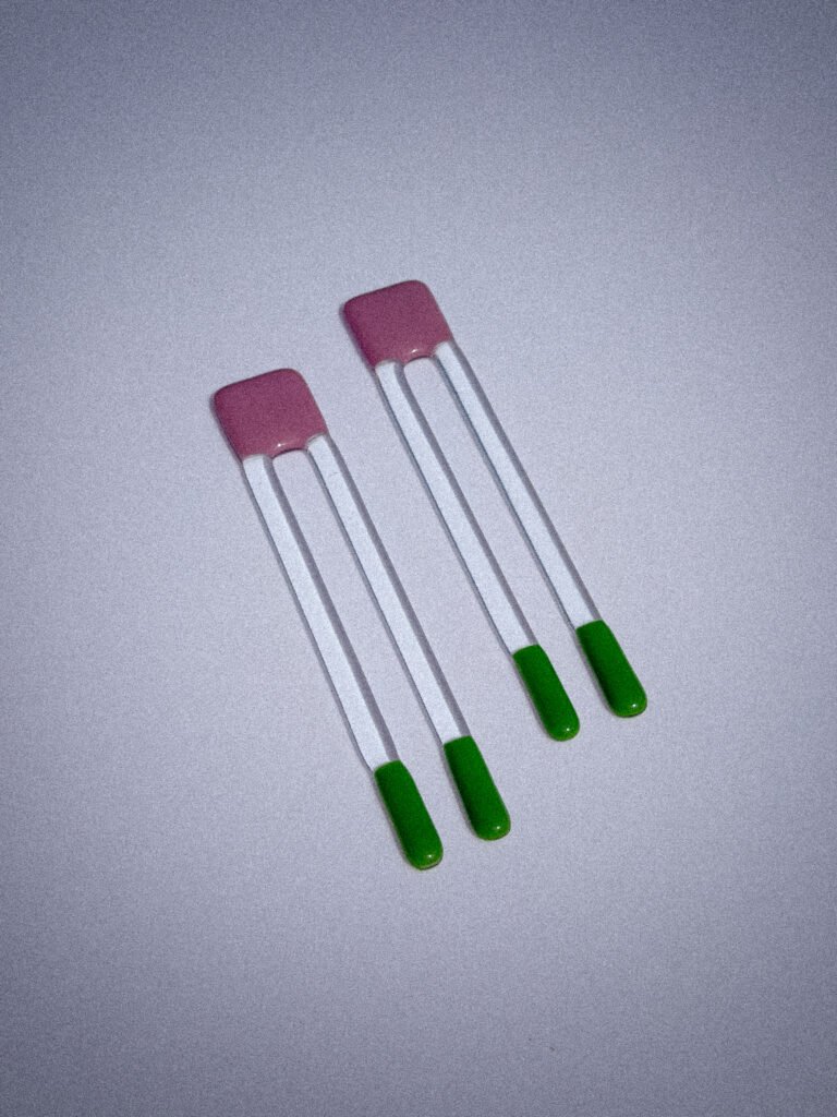 Handgemaakte glazen Pool Sticks in paars en groen op een witte tafel.