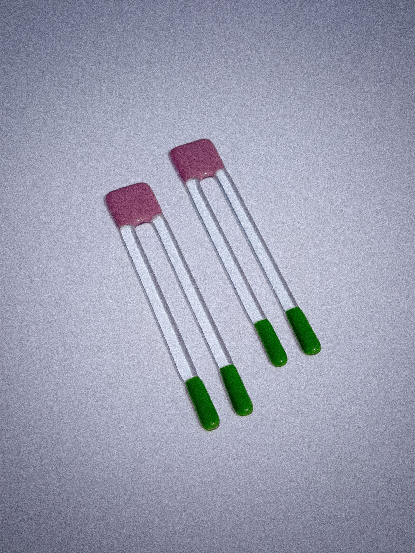 Handgemaakte glazen Pool Sticks in paars en groen op een witte tafel.