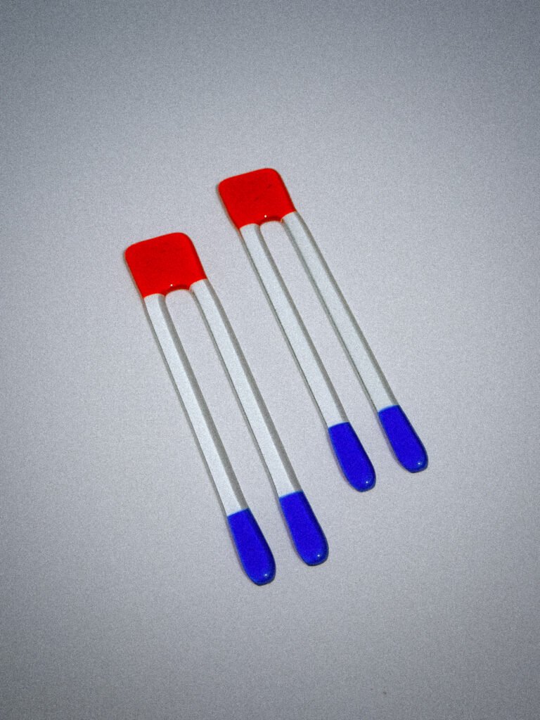 Handgemaakte glazen Pool Sticks in rood en blauw op een witte tafel.